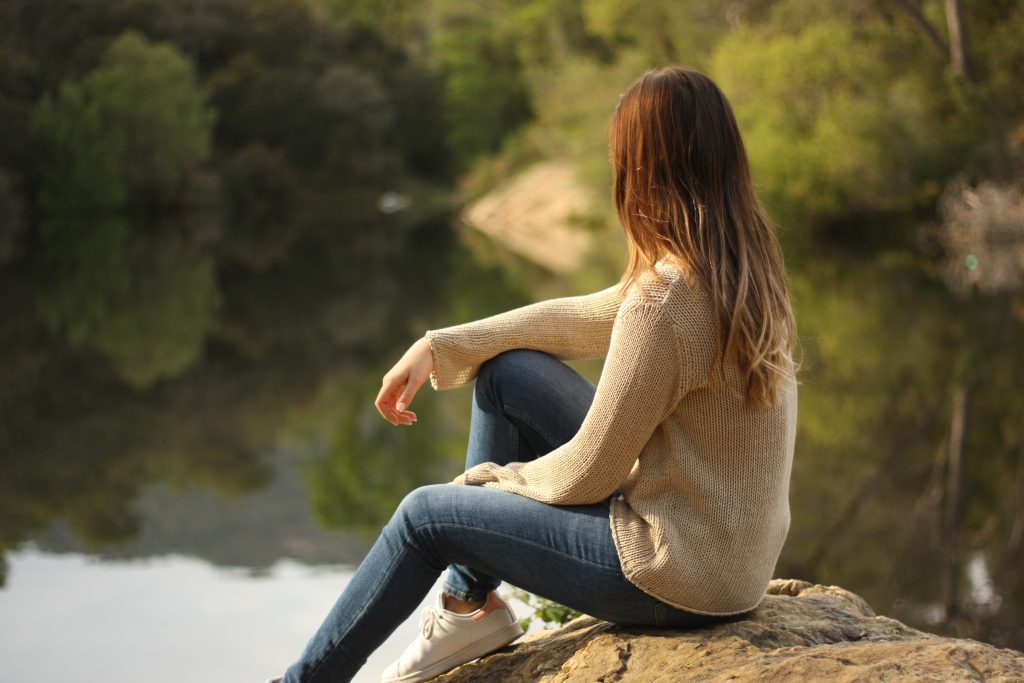 A woman by a lake peacefully looking out over the water.  Finding God's peace in uncertain times

