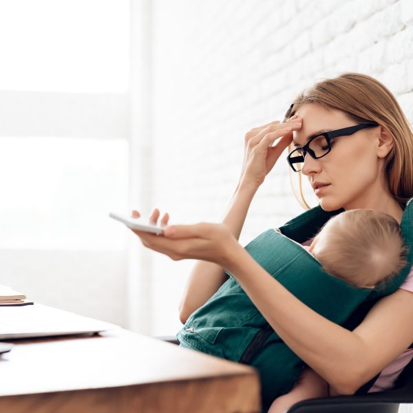 Woman with sleeping baby at computer-worn out. Finding strength in God when you feel weak and worn out
