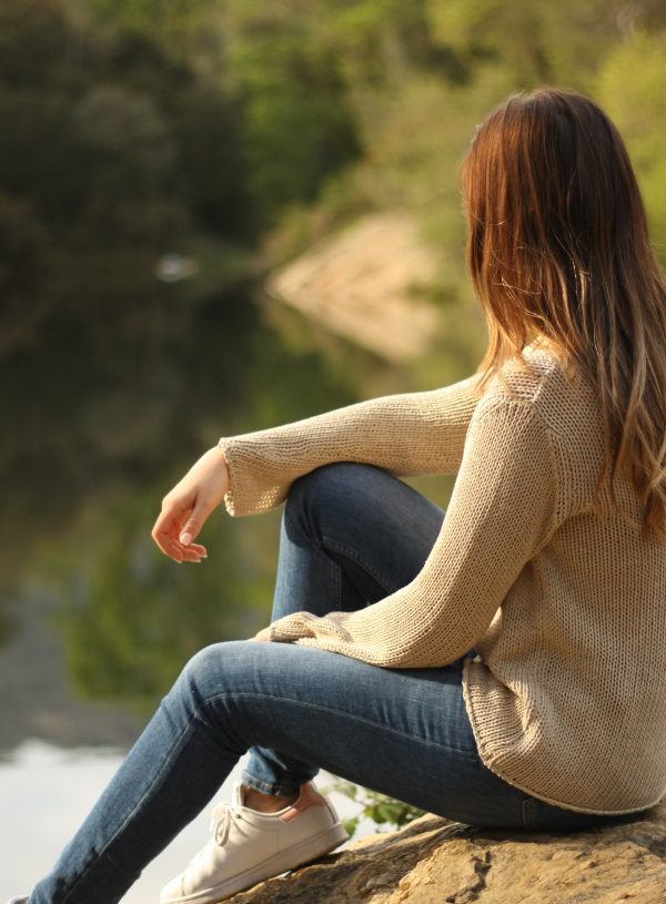 A woman by a lake peacefully looking out over the water. Finding God's peace in uncertain times